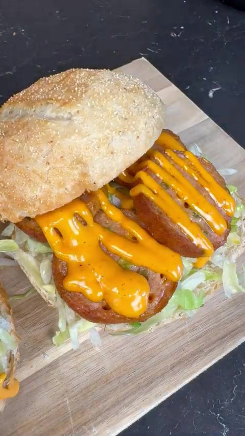 Knuspriges Brötchen mit Hähnchen-Grillwurst, Eisbergsalat und Cheddarsoße