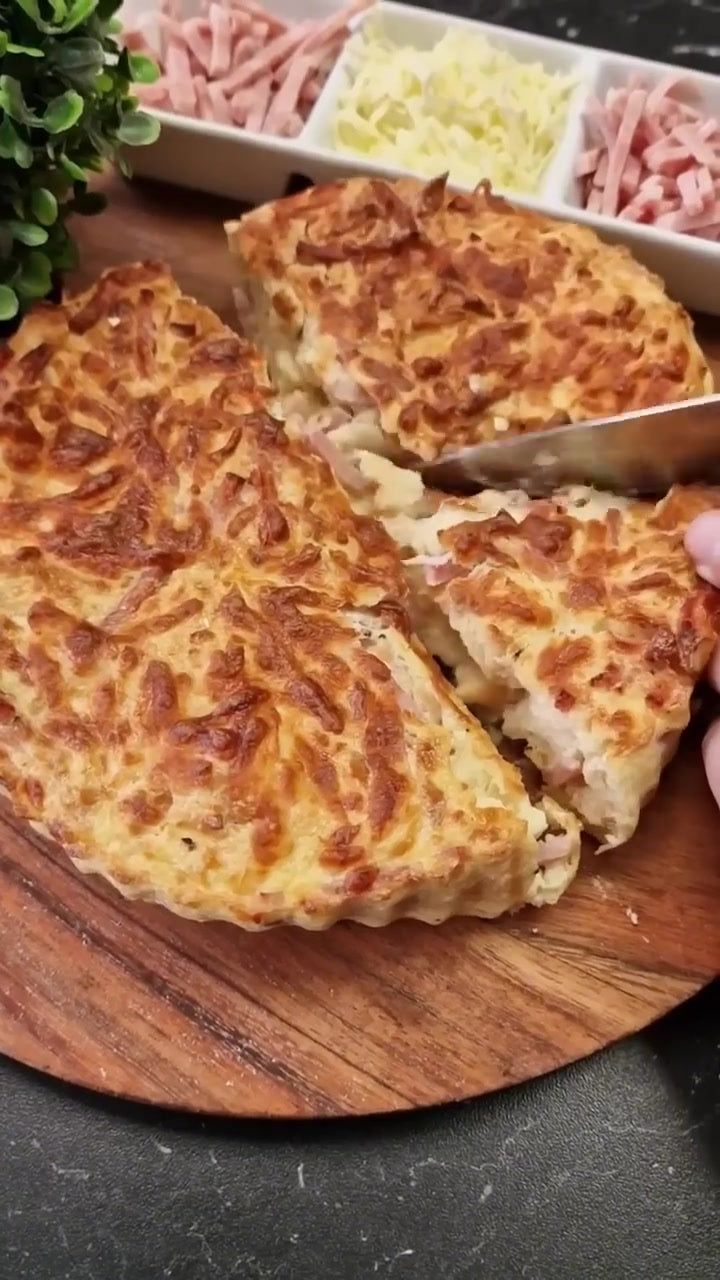 Goldbrauner Brotkuchen mit Schinken und Käse, auf einem Holzbrett in Stücke geschnitten