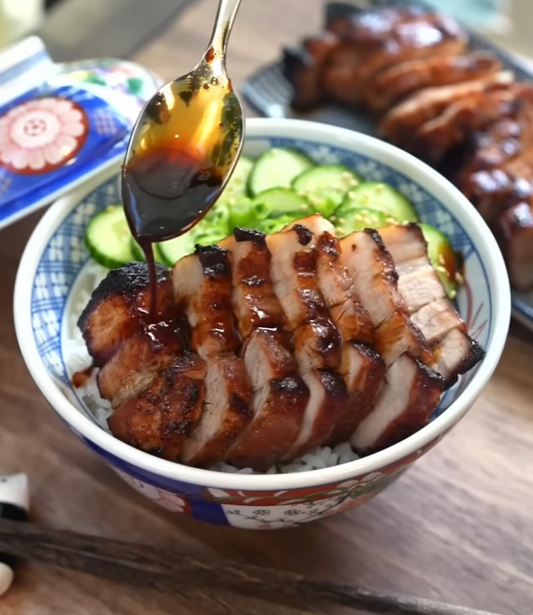 Aufgeschnittener honigglasierter Schweinebauch mit Reis und Gurke