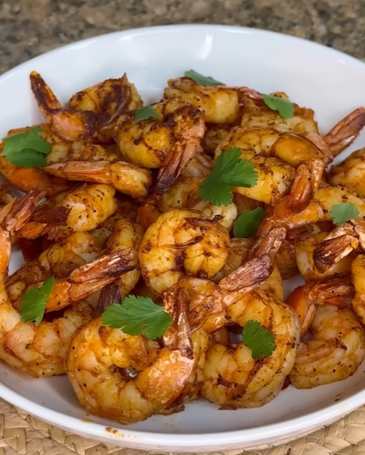 Pikant gewürzte Airfryer-Garnelen mit frischem Koriander auf einer weißen Platte