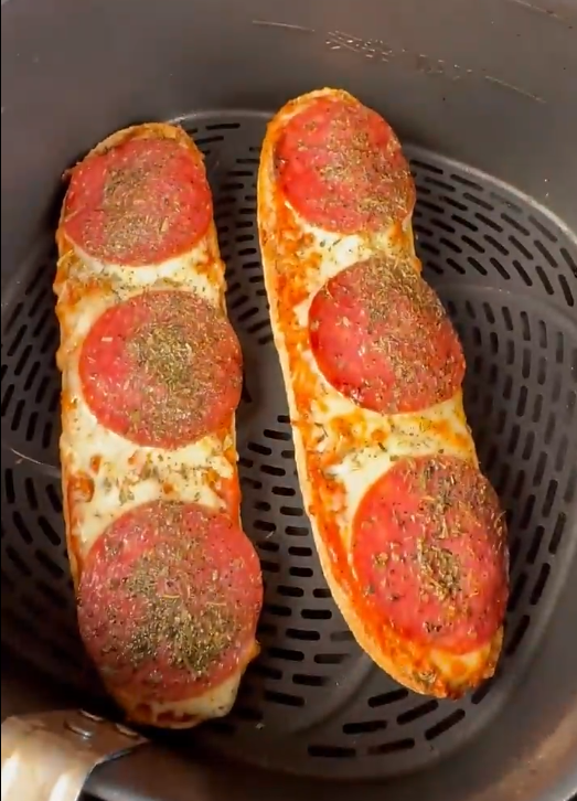 Zwei gebackene Pizza-Baguettes mit Salami, geschmolzenem Käse und italienischen Kräutern im Airfryer